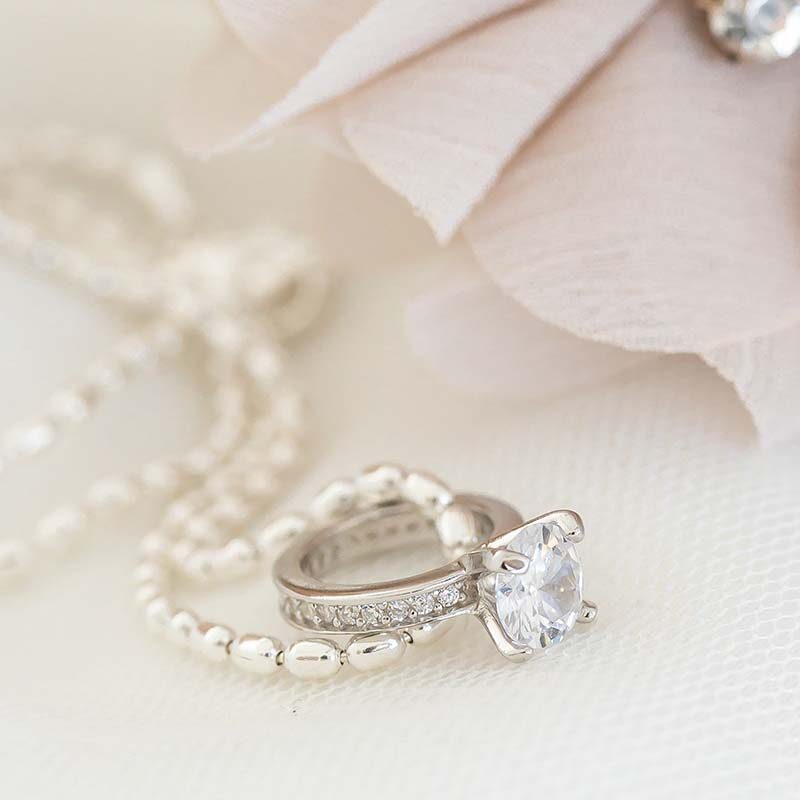 Nuppu kastesormus kirkkaalla kivellä ja oliiviketju