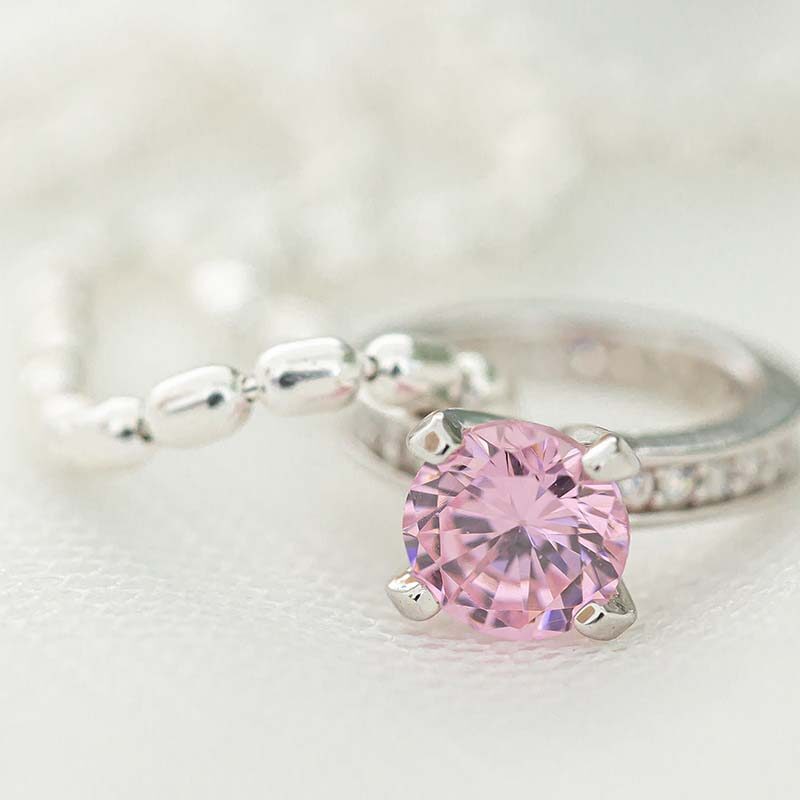 Nuppu kastesormus pinkillä kivellä ja oliiviketju